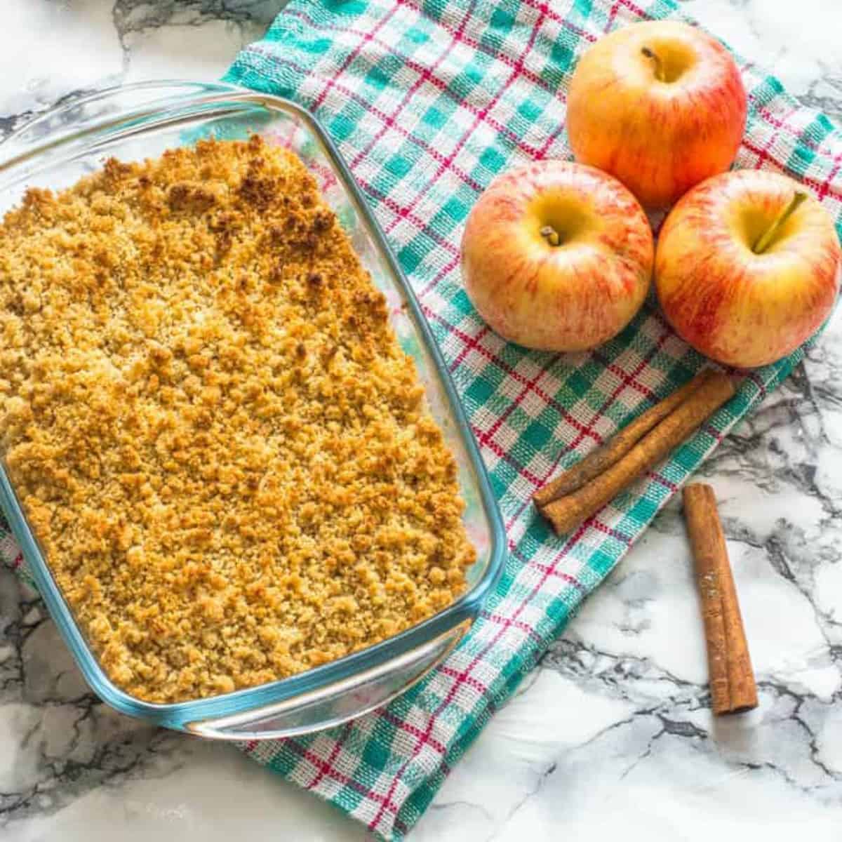 apple crisp in a pyrex next to red apples