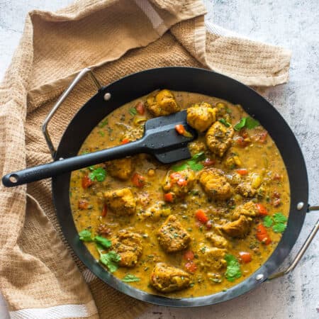 Black spatula rest on the pan of curry