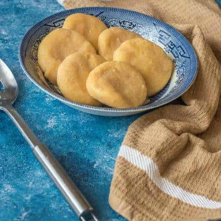 Jamaican cornmeal dumpling Six dumpling with a spoon with a blue bowl