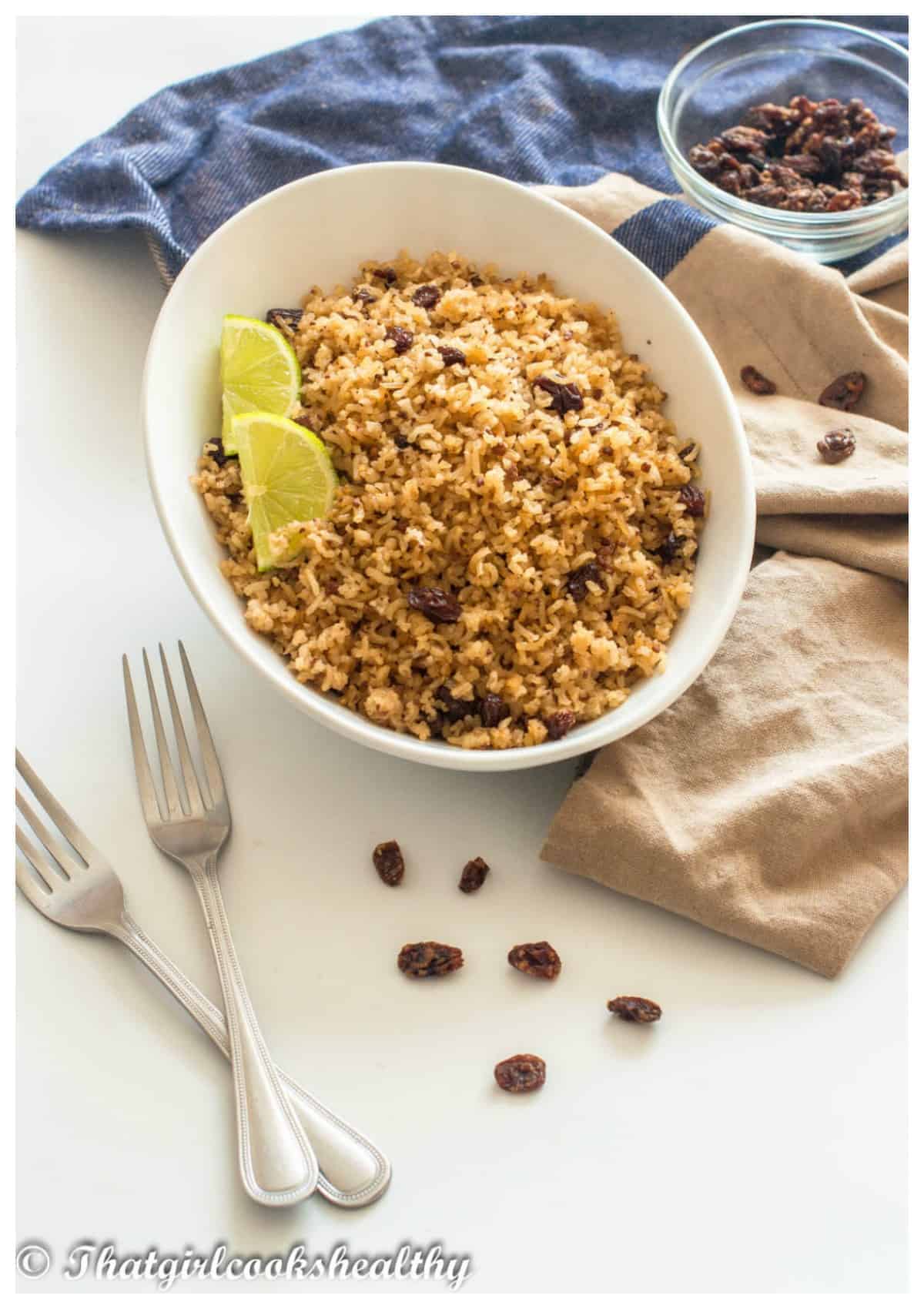 bowl of rice on a cloth with fork and raisins