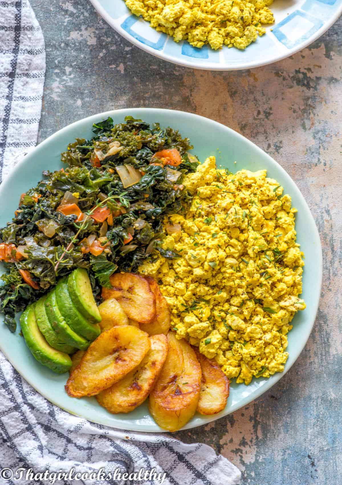 plate of scrambled tofu, plantain, avocado and greens