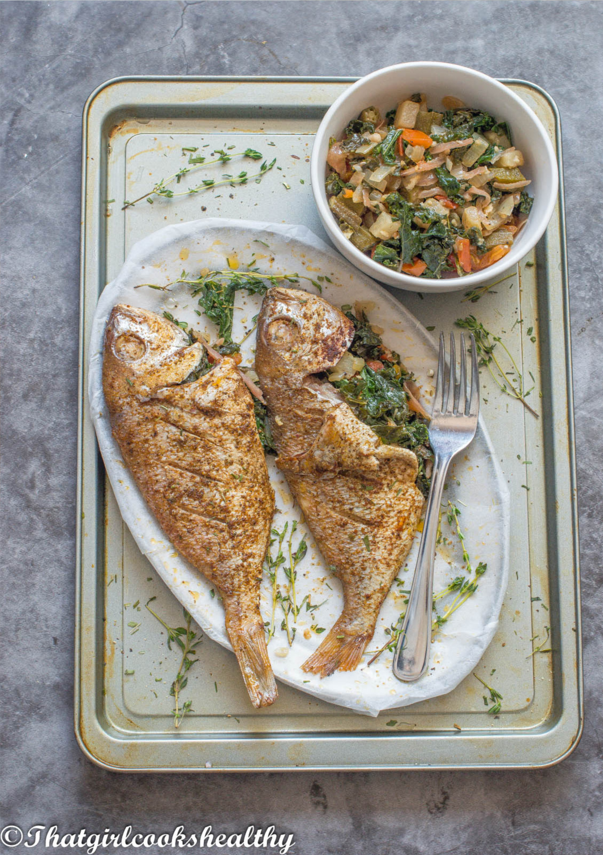 2 fish on a tray with vegetables