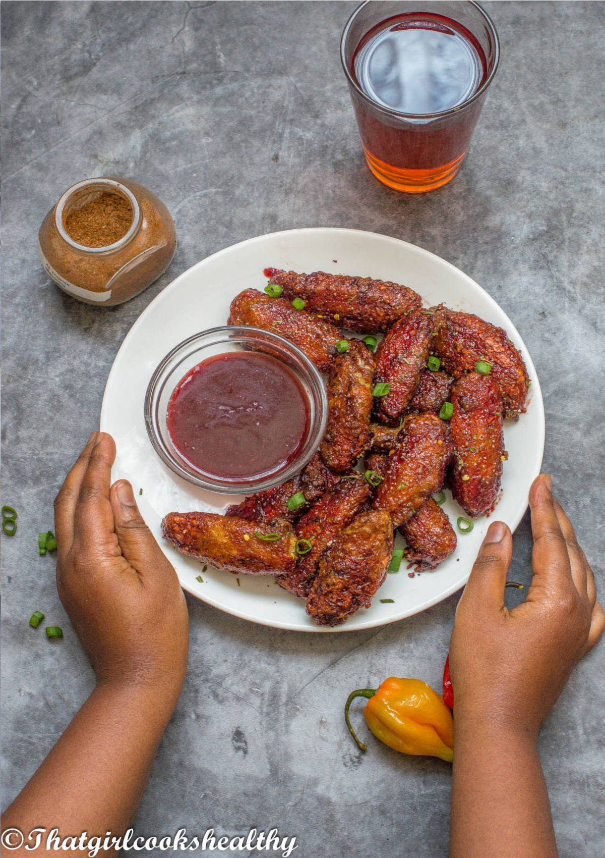 A pair of hands holding a plate of chicken wings