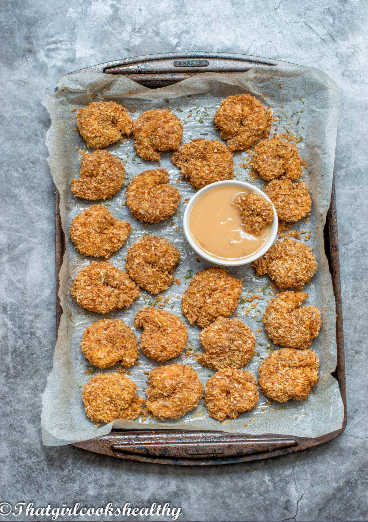 Baked shrimp on a baking tray with dipping sauce