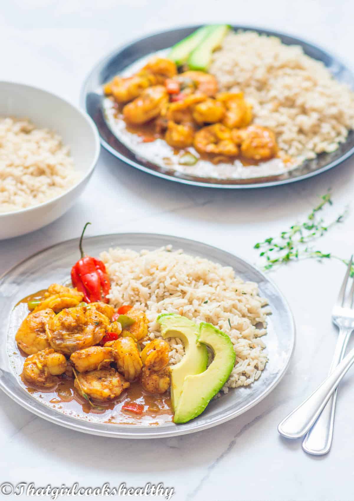 Shrimp on a grey plate with brown rice and avocado
