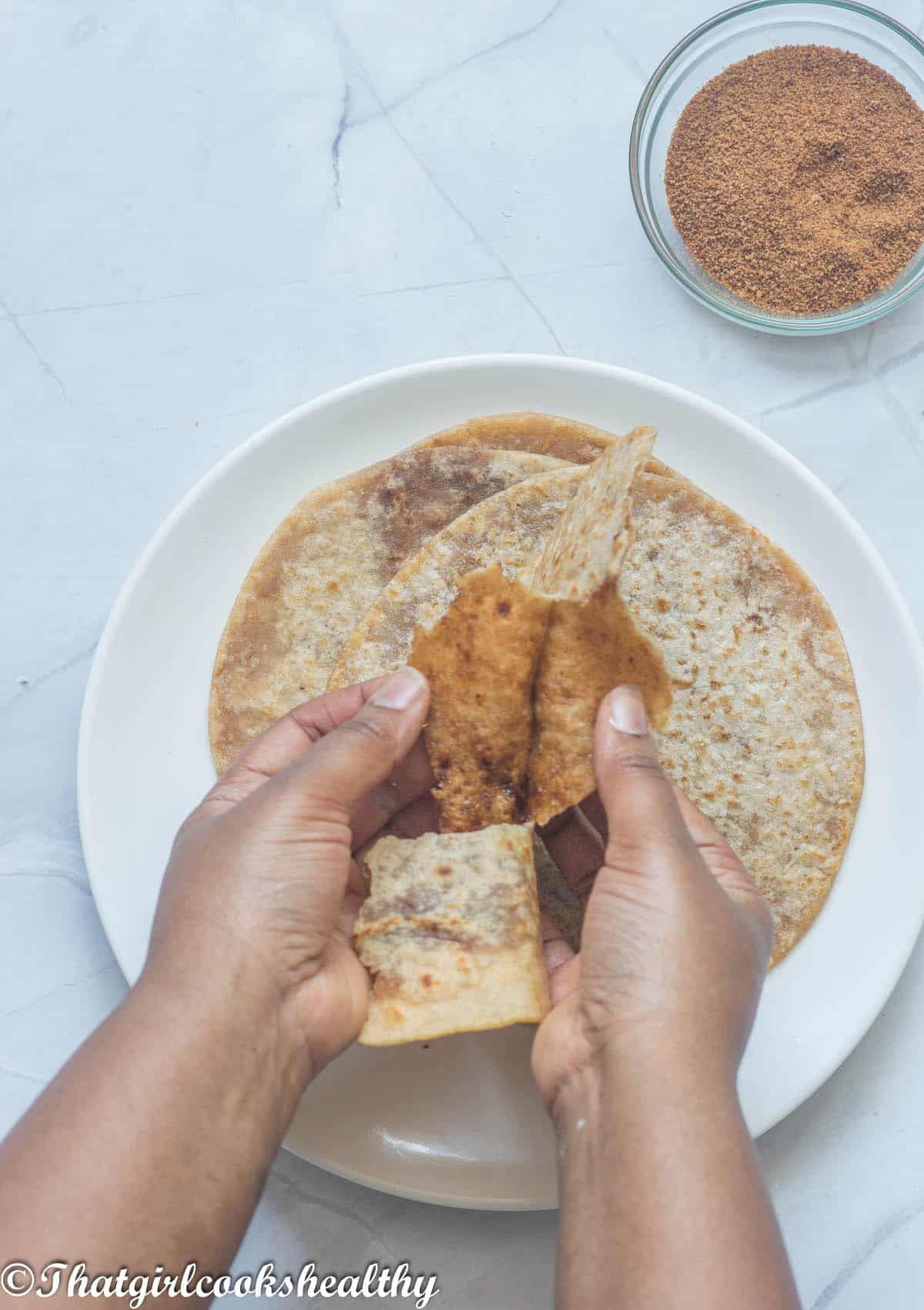 A pair of hands opening up the roti.
