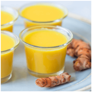Small shot glasses with fresh turmeric on a plate