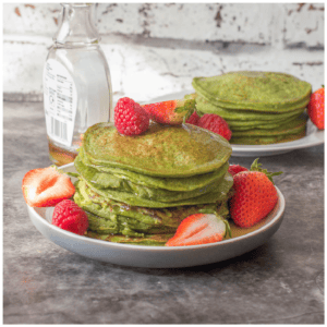 A stack of green pancakes with fruit