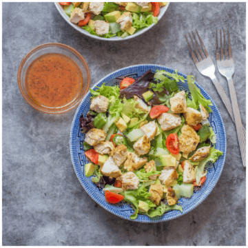 A blue bowl of mixed salad with chicken