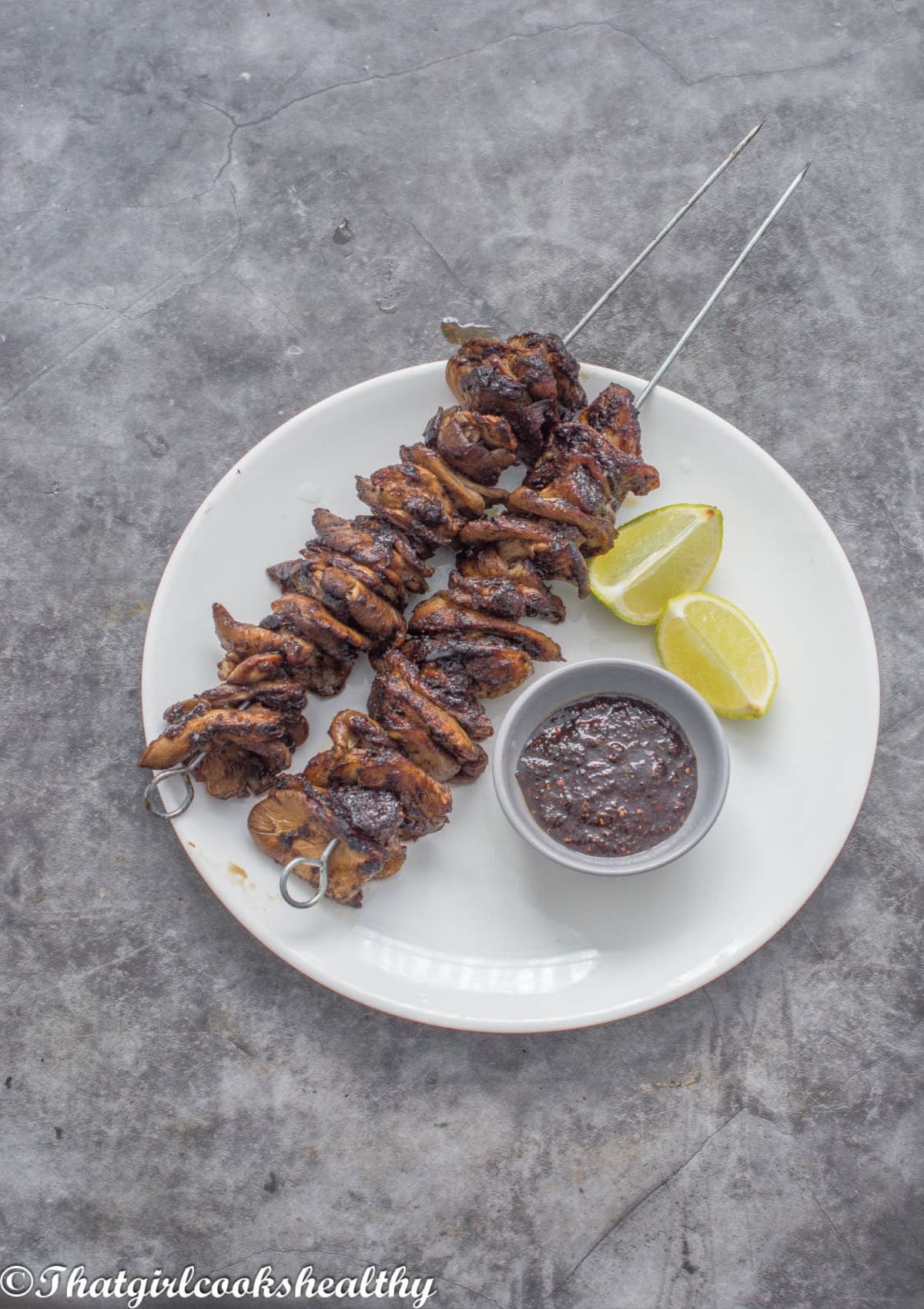 2 jerk oyster mushrooms on a skewer with lime and sauce