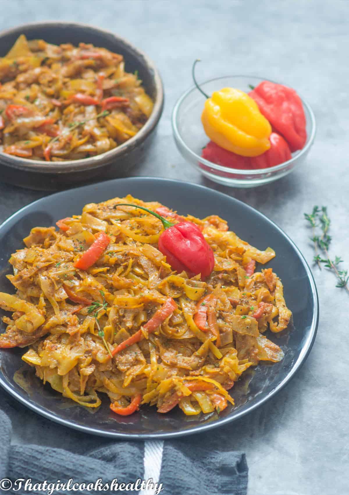 cabbage on a black plate with scotch bonnet peppers