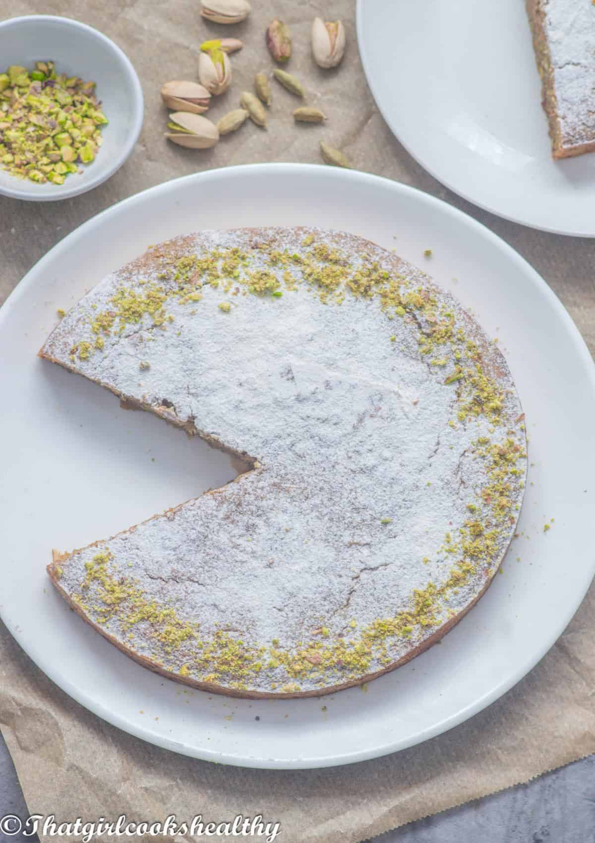 a cut cake dusted with powdered sugar and garnished with nuts