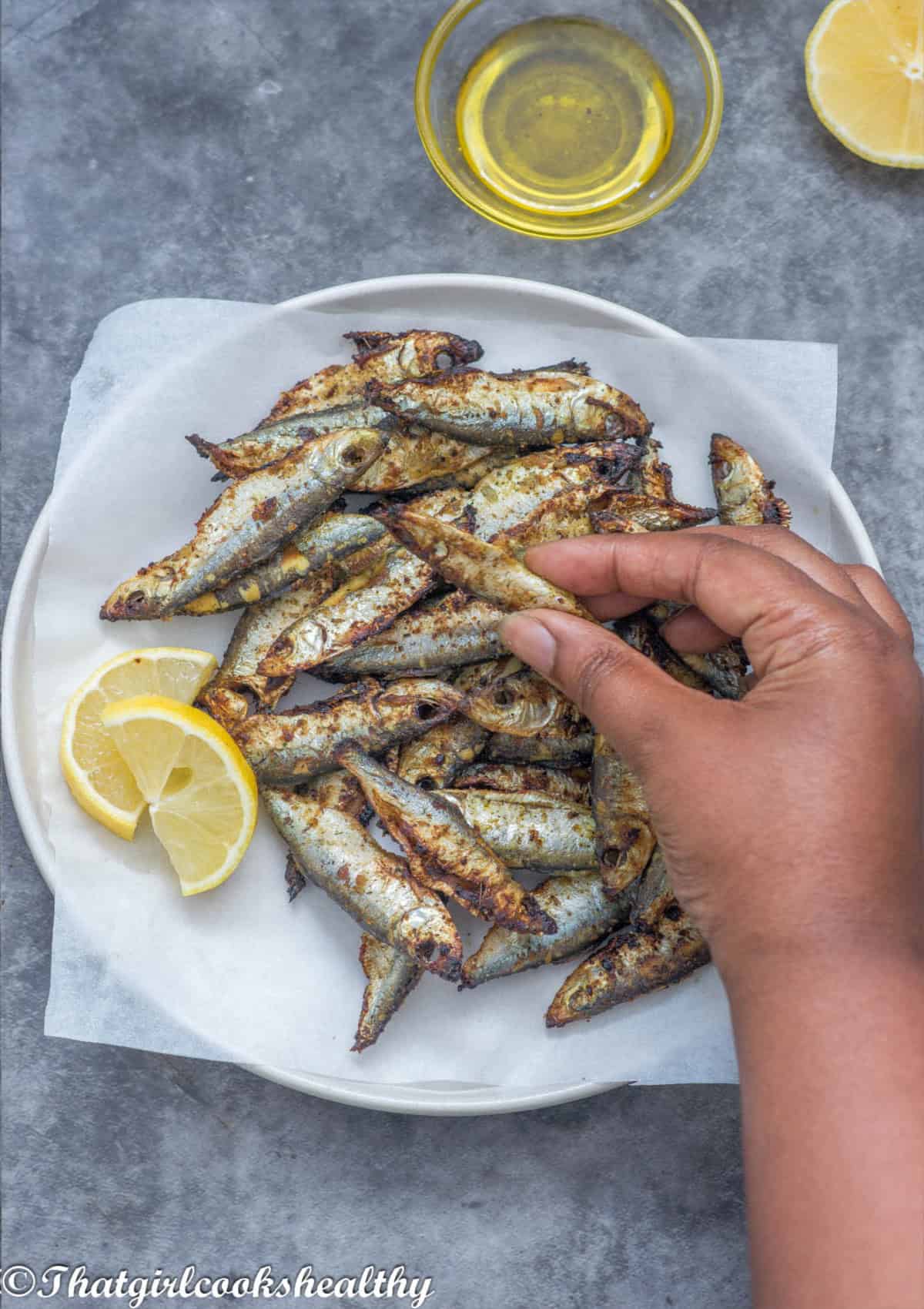 Fingers picking up the sprats
