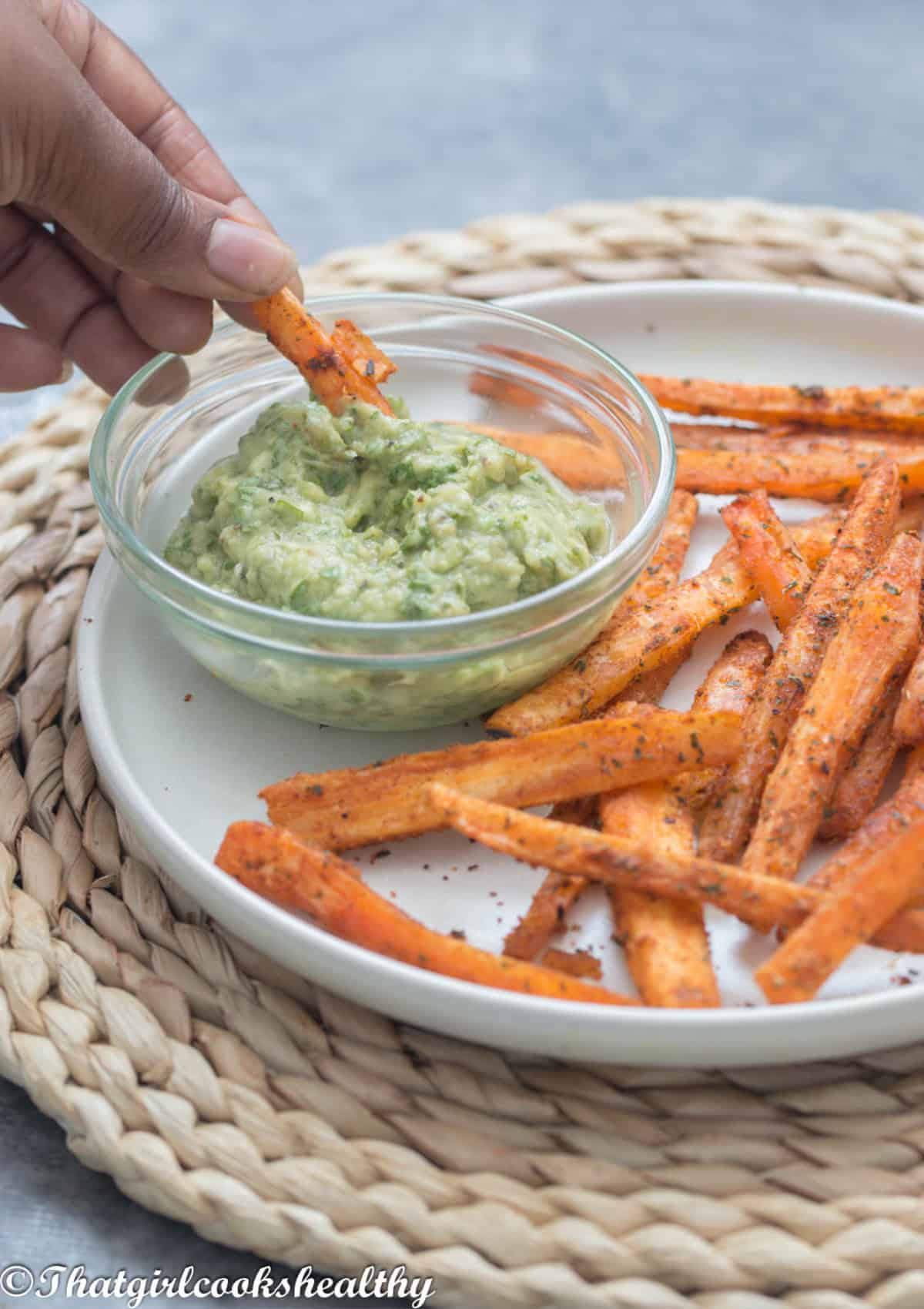 Hands dipping the fries into the dip